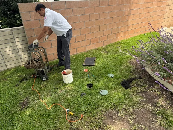 Technician preparing a sewer line camera inspection through an outdoor cleanout